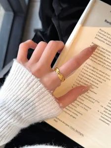 Gros plan d'une bague torsadée dorée au doigt avec un fond de livre élégant