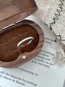 Détail macro de la bague éternité en argent 925 avec diamants sur boîte en bois de noyer