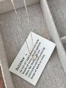 Detailed view of a gold horseshoe necklace with sparkling stones on an elegant card