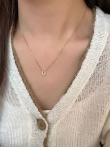 Close-up of a gold U-shaped horseshoe pendant with pavé diamonds on a model's neck
