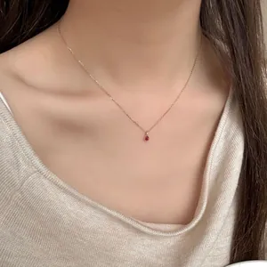 Elegant S925 silver necklace with red teardrop gemstone on a gold chain worn by model