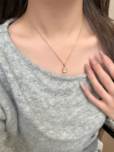 Dettaglio collana in argento S925 con pendente in zircone tondo indossata su maglione