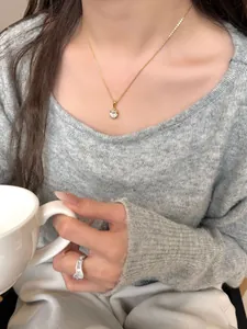 Dettaglio di una collana dorata con zircone ovale indossata da una modella