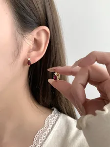 Close-up of S925 silver gold-plated stud earrings with oval red gemstone and zircon