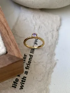 Détail d'une bague en argent doré avec texture perlée et pierre précieuse violette