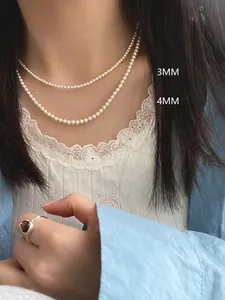 Detail of 3mm and 4mm round pearl necklaces on a model with a silver gemstone ring