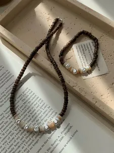 Dettaglio del bracciale e collana in argento S925 e perle di cocco su un libro