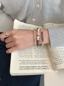 Dettaglio di bracciali di perline in argento S925 e anello con gemma su libro