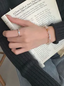 Dettaglio anello in argento con gemma blu e bracciale di perle colorate sulla mano
