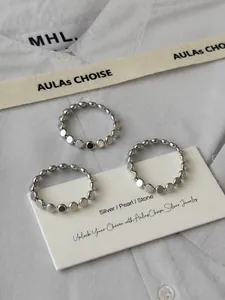 Détails de trois bagues perlées minimalistes en argent sterling S925 sur tissu blanc