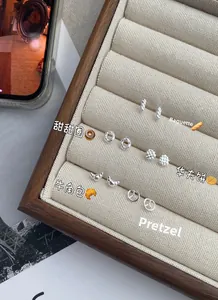 Dettaglio ravvicinato di orecchini in argento 925 con forme di mini baguette e croissant