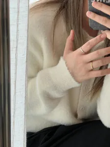 Détail de bagues plissées minimalistes argentées et dorées avec un gilet blanc doux