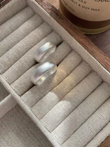 Close-up of two matte S925 sterling silver minimalist rings in a wooden jewelry box