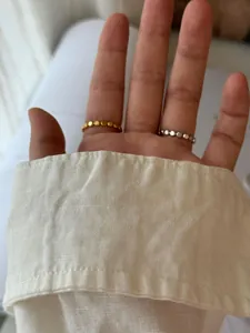 Gros plan de bagues minimalistes en perles d'or et d'argent portées pour un look superposé
