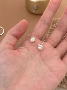 Vue détaillée des boucles d'oreilles nœud en argent S925 avec perles d'eau douce en main