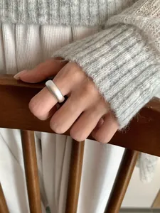 Matte silver wide band ring worn by model in a cozy lifestyle setting showing texture