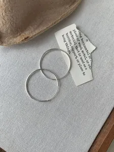 Detail von hochglanzpolierten S925-Sterlingsilber-Creolen auf Vintage-Strukturhintergrund