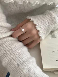 Detalle de anillo minimalista de plata en el dedo índice con un fondo de punto acogedor