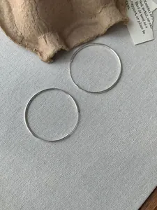 Detailansicht großer dünner S925 Sterling Silber Creolen auf grauem Stoff