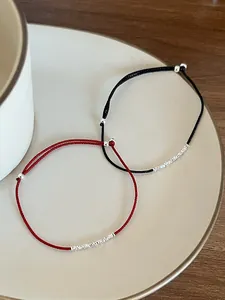 Dettaglio di braccialetti intrecciati rossi e neri con piccole perline d'argento