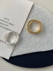 Dettaglio di anelli intrecciati in finitura oro e argento con superficie lucida a specchio