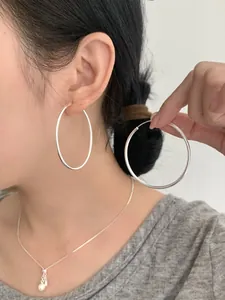 Nahaufnahme einer großen silbernen Creole am Modell für einen minimalistischen Look