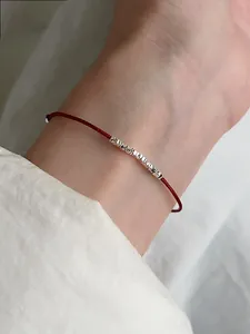 Dettaglio del bracciale con cordino rosso e perline in argento sterling testurizzato in stile minimalista