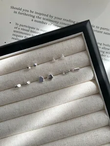 Detalle macro de pendientes geométricos de plata de ley S925 en una bandeja de joyas