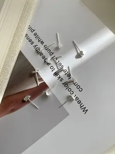 Primer plano de pendientes geométricos minimalistas de plata S925 sobre una revista