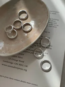 Dettaglio di anelli minimalisti in argento 925 su piatto in ceramica con libro