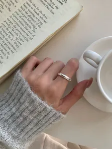 Primo piano di un anello minimalista in argento sterling S925 lucido indossato all'indice