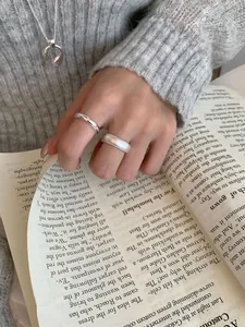Anelli in argento lucido e opaco con una collana a U su una modella per un look elegante