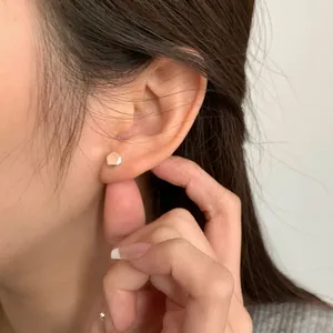 Pendiente de tuerca hexagonal minimalista de plata S925 dorada visto en el modelo