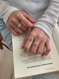 Set di quattro anelli in argento S925 con pietre preziose su sfondo di un libro