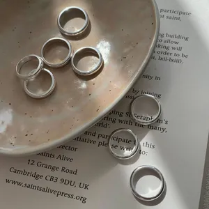 Set di anelli minimalisti in argento S925 lucido su una pagina di libro vintage