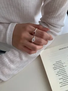 Dettagli degli anelli in argento S925 con cristalli rosa e chiari su maglia bianca