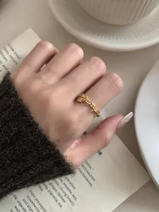 Detail van een 18K goudvergulde schakelring met hartvormige hanger om de vinger