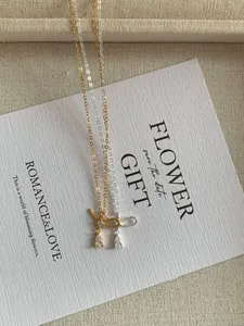 Detail of silver and gold bow necklaces with pear-cut cubic zirconia pendants