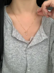 Detail of a bow-knot necklace with a teardrop zircon pendant worn by a model