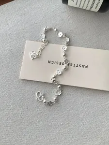 Détails des breloques fleur de pêcher et papillon en argent sur un bracelet S925 fin