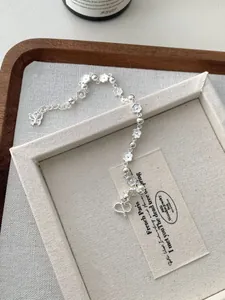 Détail macro d'un bracelet en argent S925 avec breloques fleurs et pendentif papillon