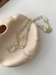 Detailaufnahme von geschichteten Silber- und Goldperlenketten mit Karabinerverschlüssen