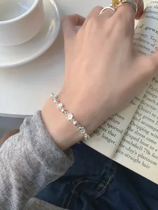Détails du bracelet en argent avec fleurs et bagues avec pierres fines sur la main
