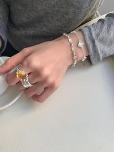 Vue détaillée du bracelet trèfle en argent et chaîne fleurie avec bague en pierre jaune