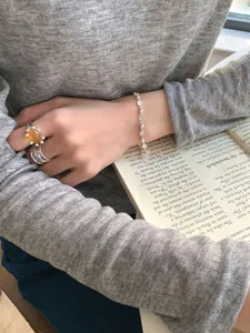 Détail du bracelet marguerite en argent et bague en argent avec pierre ambre jaune