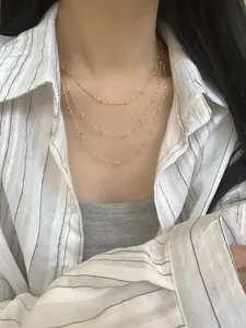 Detail einer dreilagigen goldenen Kugelkette mit Metallperlen an einem Modell