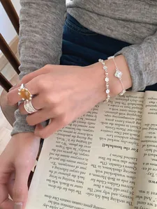 Détail d'un ensemble de bracelets trèfle et fleurs en argent S925 sur un mannequin