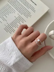 Dettaglio di anelli sovrapponibili minimalisti in argento S925 con zircone solitario