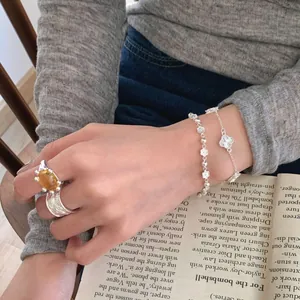 Élégant bracelet trèfle en argent S925 et bague avec ambre posés sur un livre