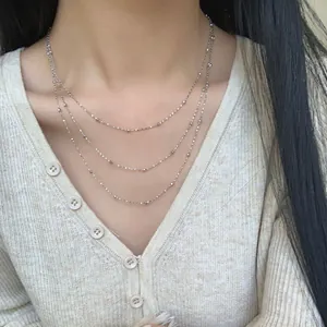 Dreilagige S925 Sterling Silber Perlenkette für Damen getragen auf beige Strickjacke